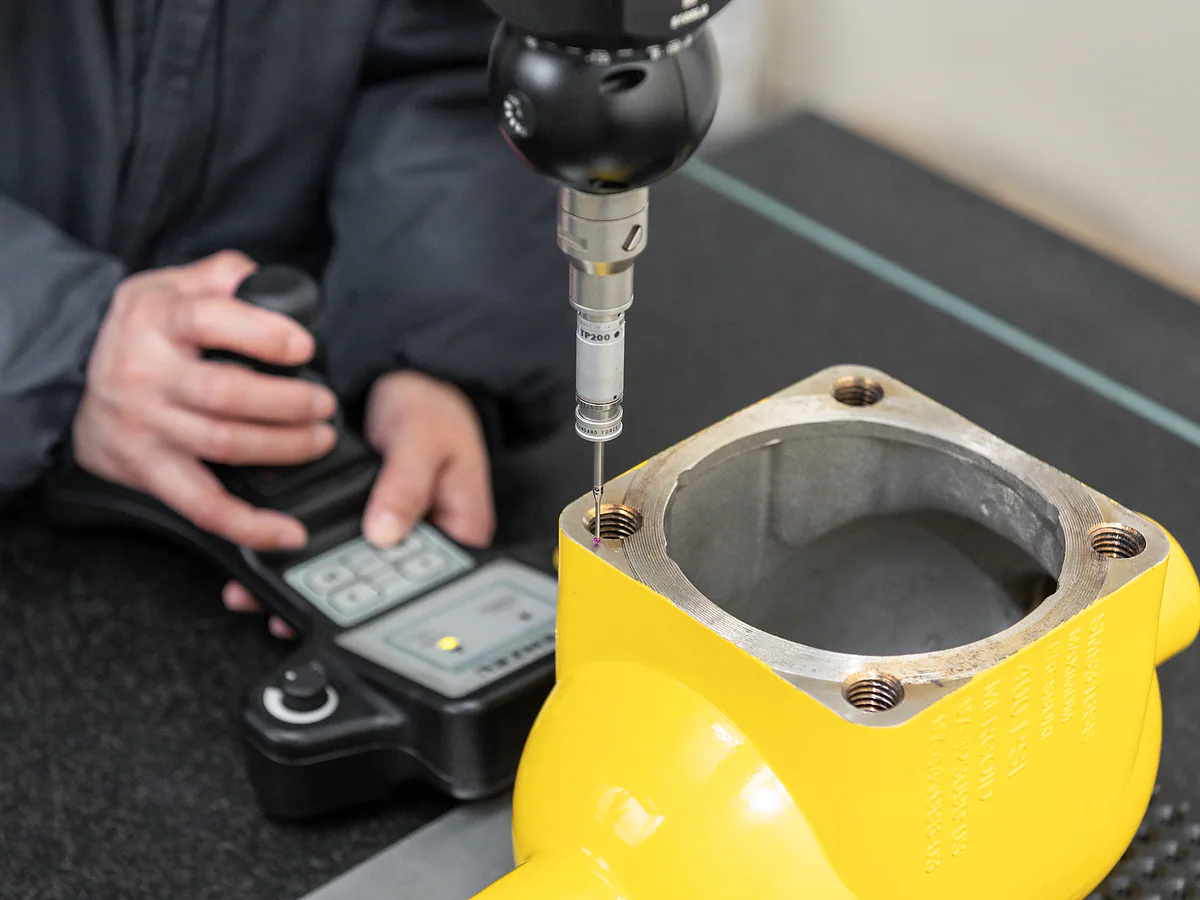Worker measuring a cast component with dimensional inspection equipment